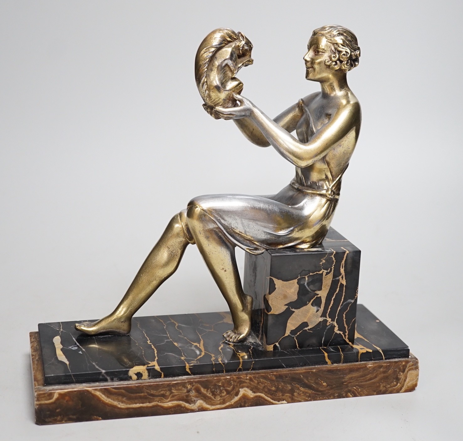 An Art Deco spelter gilded and silvered seated lady holding a squirrel, on marble and onyx mount, signed J. Dauvergne. 26cm tall